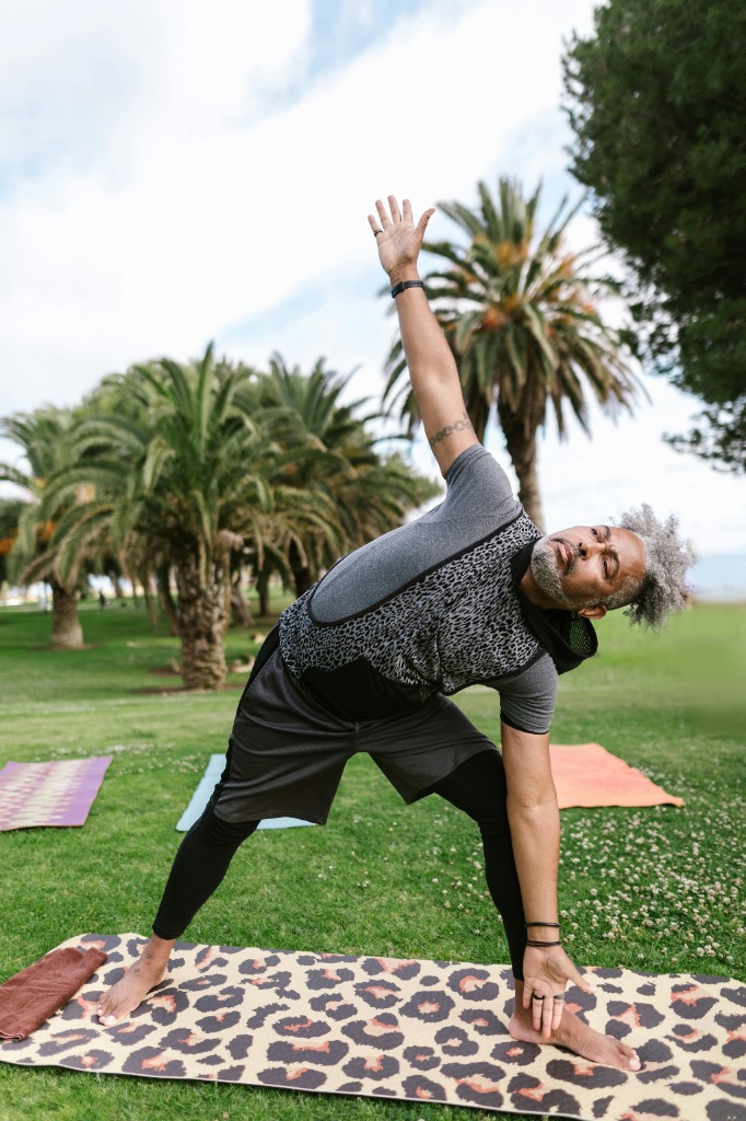 Man performing Triangle pose in park